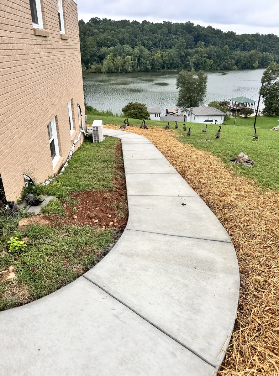 Sweeping curved concrete walkway following the grade beside a lakefront home in the NC Foothills &mdash; The Foothills Concrete Company